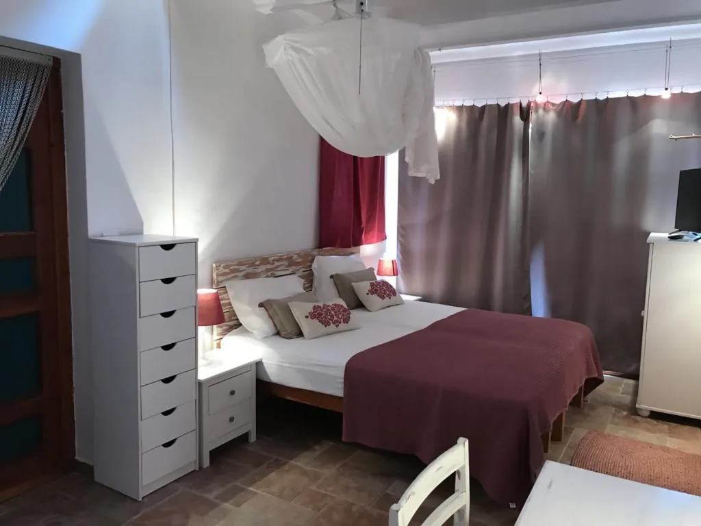 Dormitorio con dosel de tela blanca y cortinas granate, Casa Goro