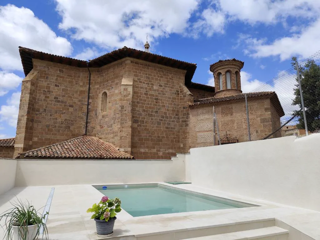 Piscina pequeña en un patio blanco junto a la torre de ladrillo