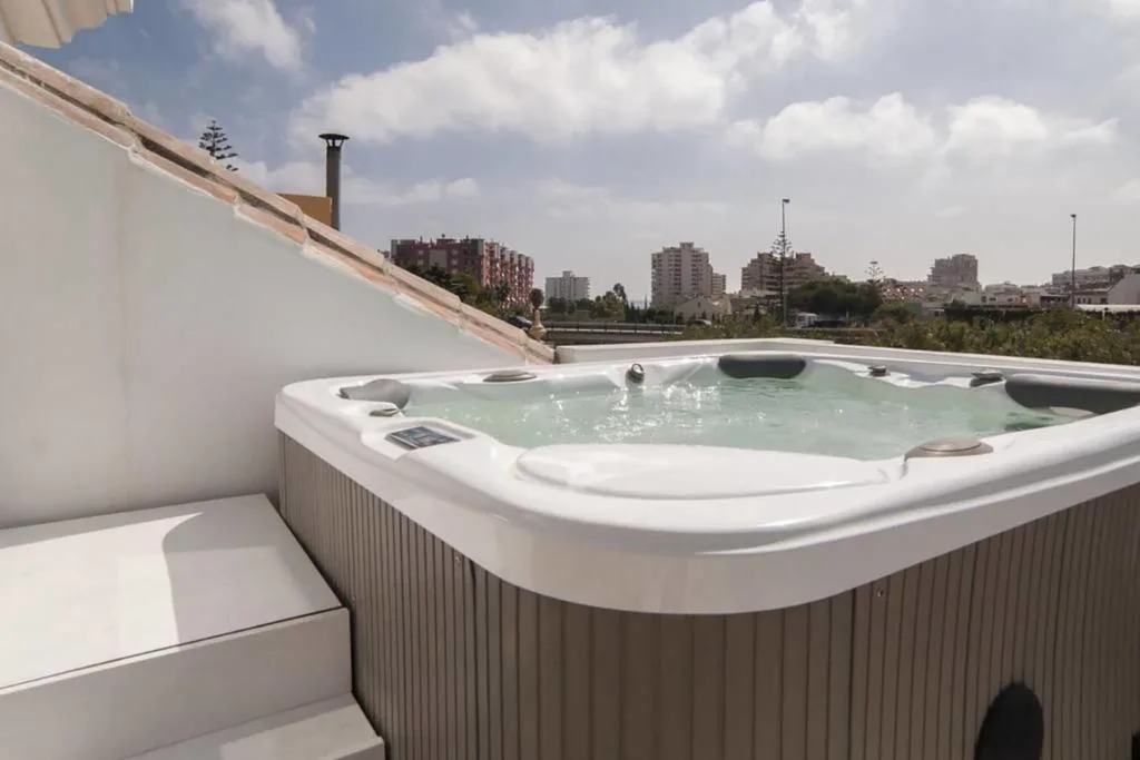 Jacuzzi en la azotea de una casa blanca con vistas a la ciudad