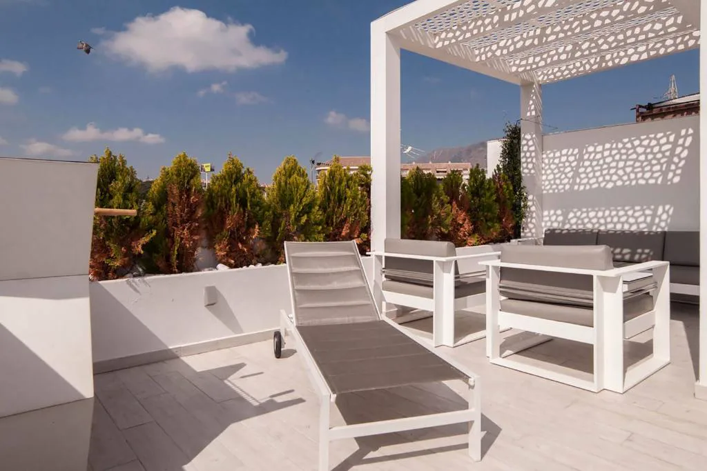 Terraza con pérgola blanca, tumbonas y sofás