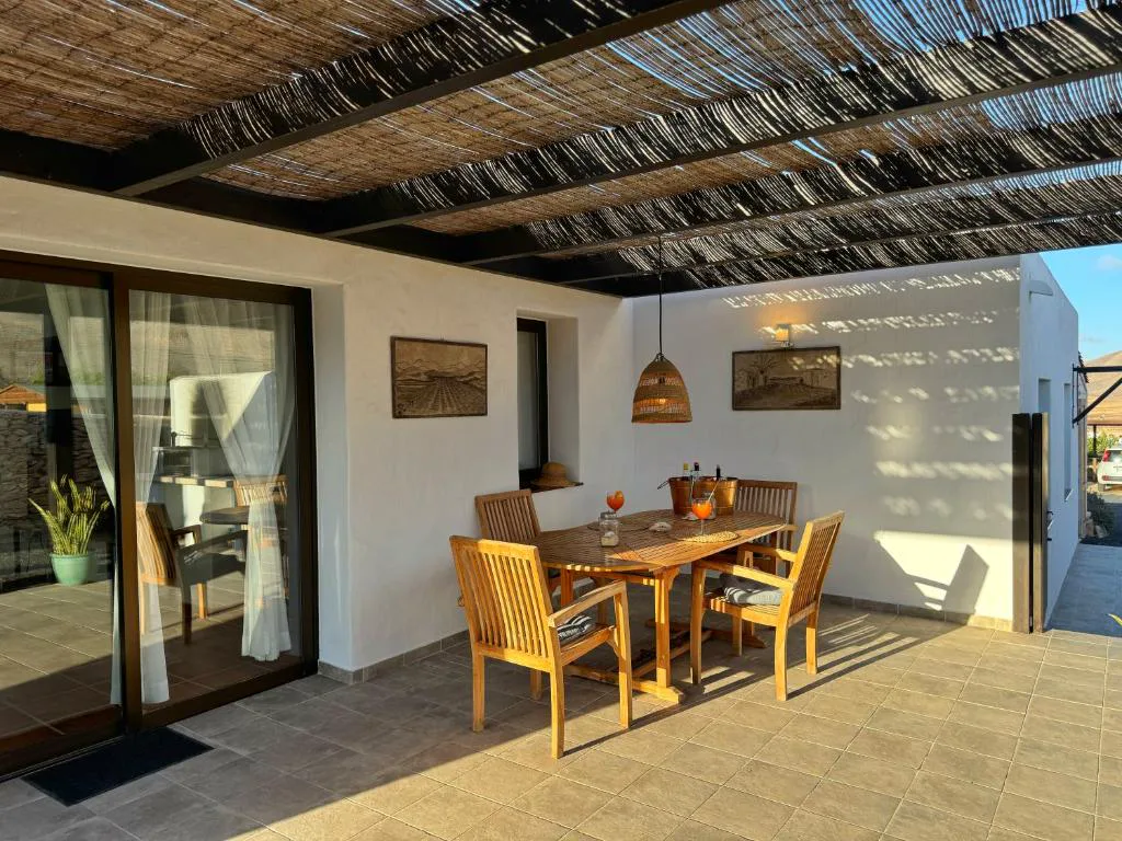 Terraza cubierta de cañizo con mesa de madera y cócteles servidos, Casa Marisa