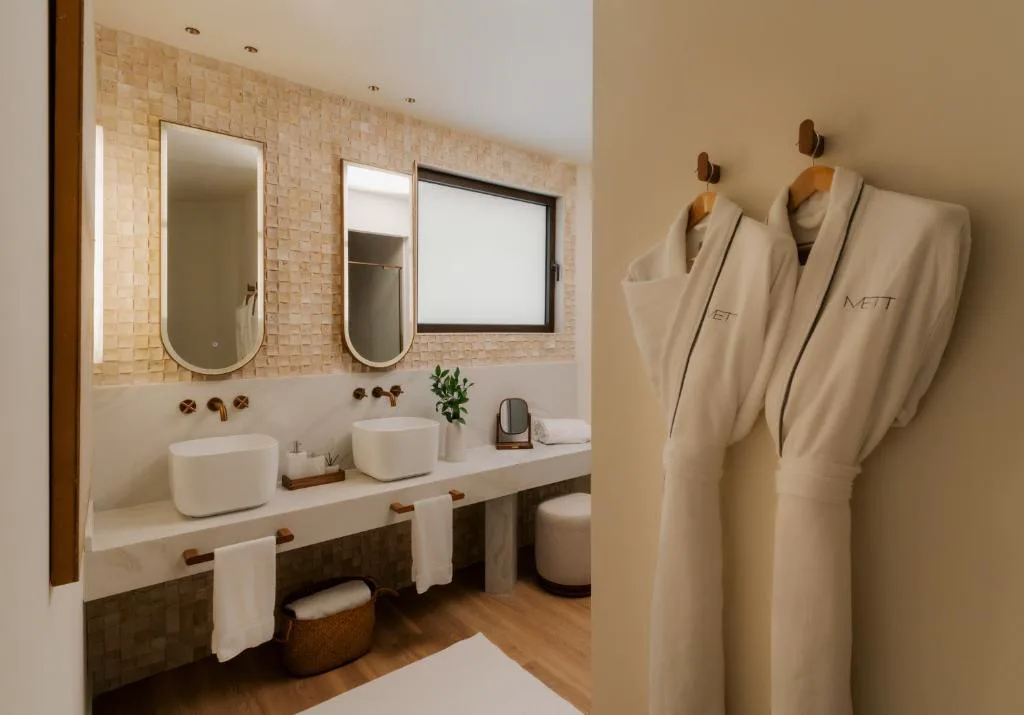 Baño con albornoces colgados y doble lavabo