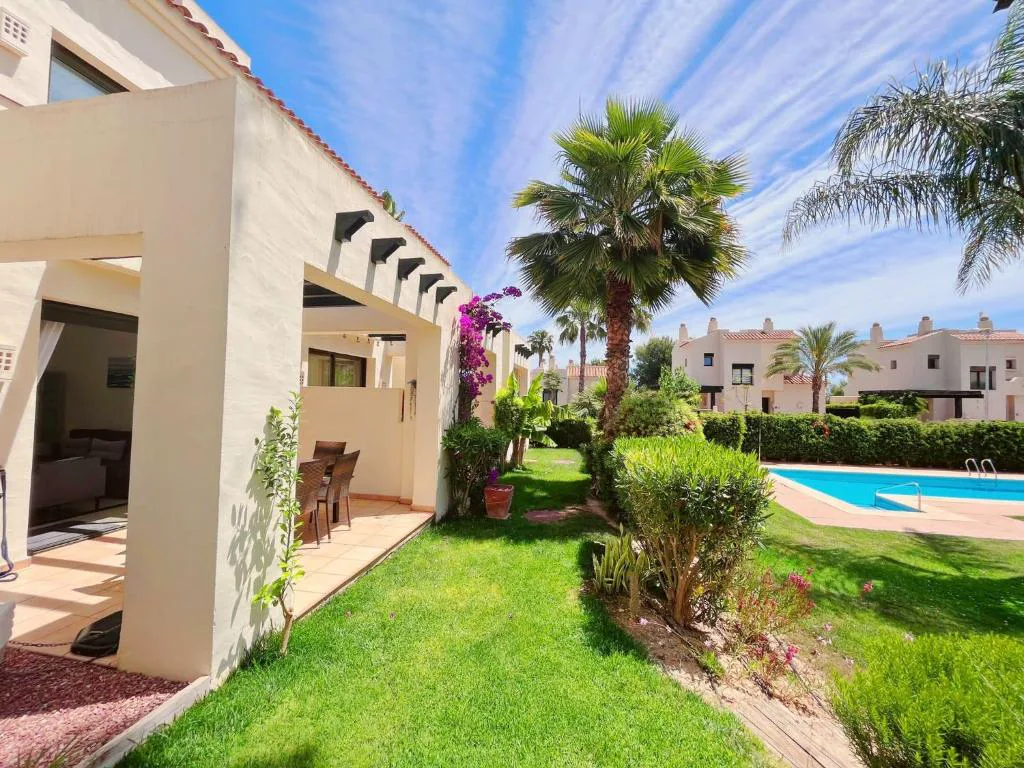 Adosado blanco con jardín y pérgola junto a la piscina