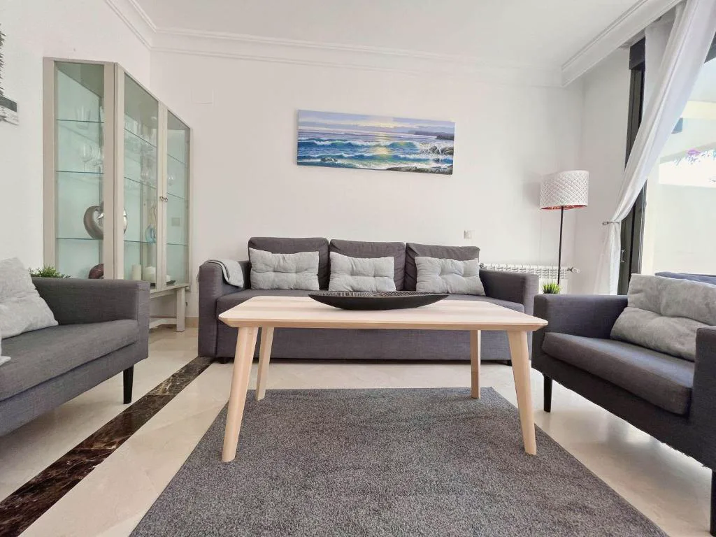 Salón con sofás negros y mesa de madera
