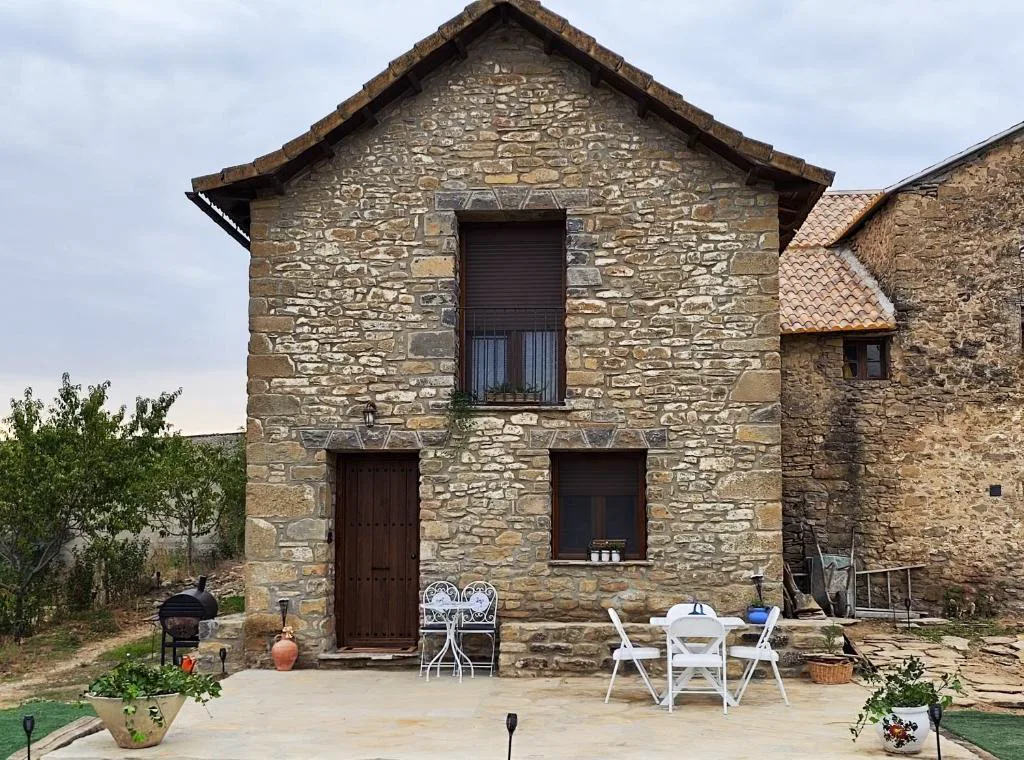 Casa de piedra con porche y mesa de terraza