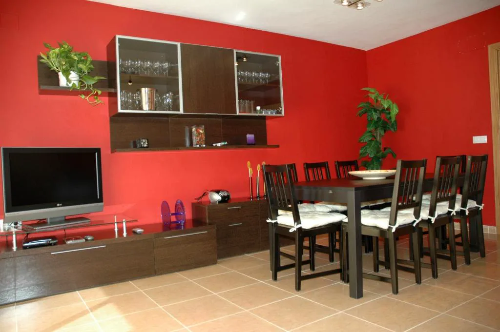 Salón con mesa de comedor y pared roja