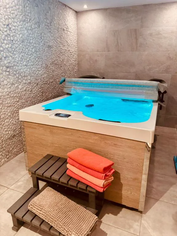 Bañera de hidromasaje con agua azul y toallas en un rincón de la casa