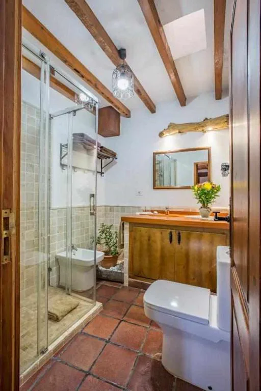 Baño con techo de vigas de madera y mueble de lavabo en madera maciza, Casa Oronado