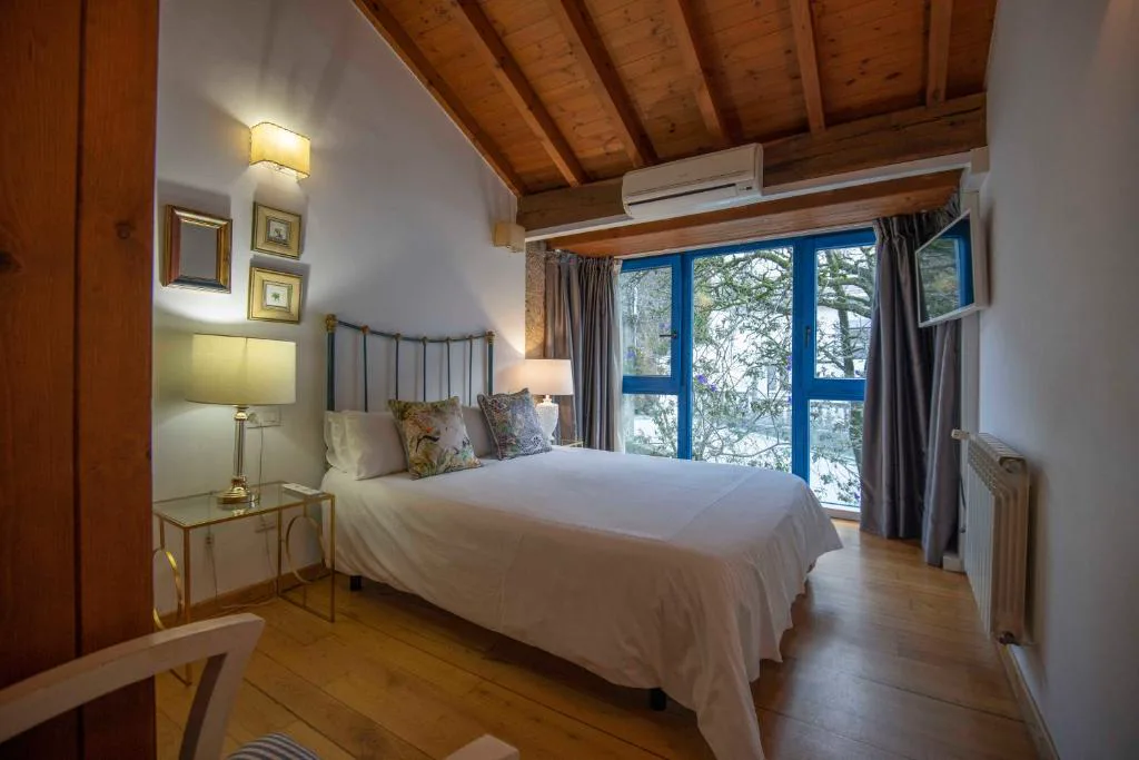 Habitación abuhardillada con cabecero de hierro forjado y vistas al jardín, Casa Perfeuto Maria