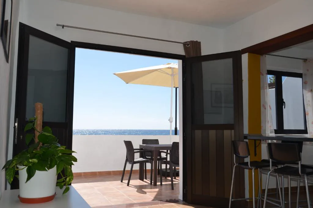 Comedor con barra alta y puerta abierta directamente al mar, Casa de la playa