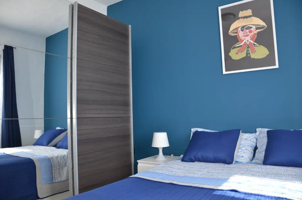 Dormitorio azul con cabecero doble y cuadro de retrato, Casa de la playa