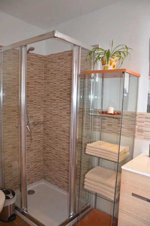Baño con ducha de mampara y estantería de cristal con toallas, Casa de la playa