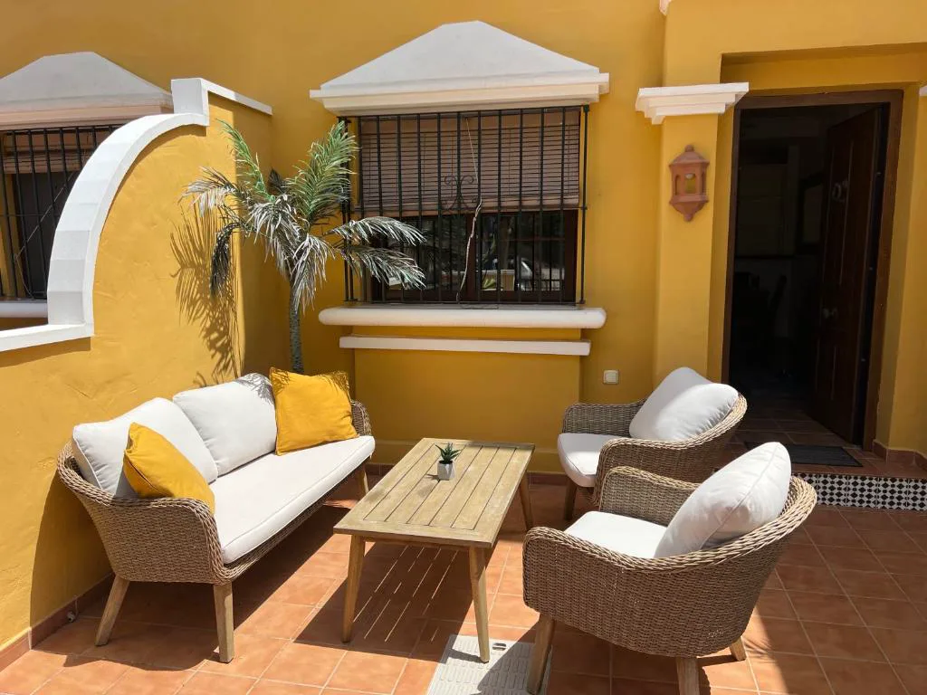 Patio con sofá blanco y sillones de mimbre