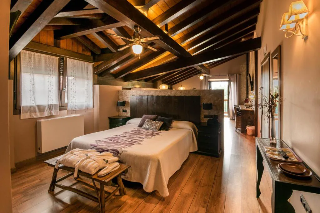 Dormitorio con cabecero de madera y techo de vigas