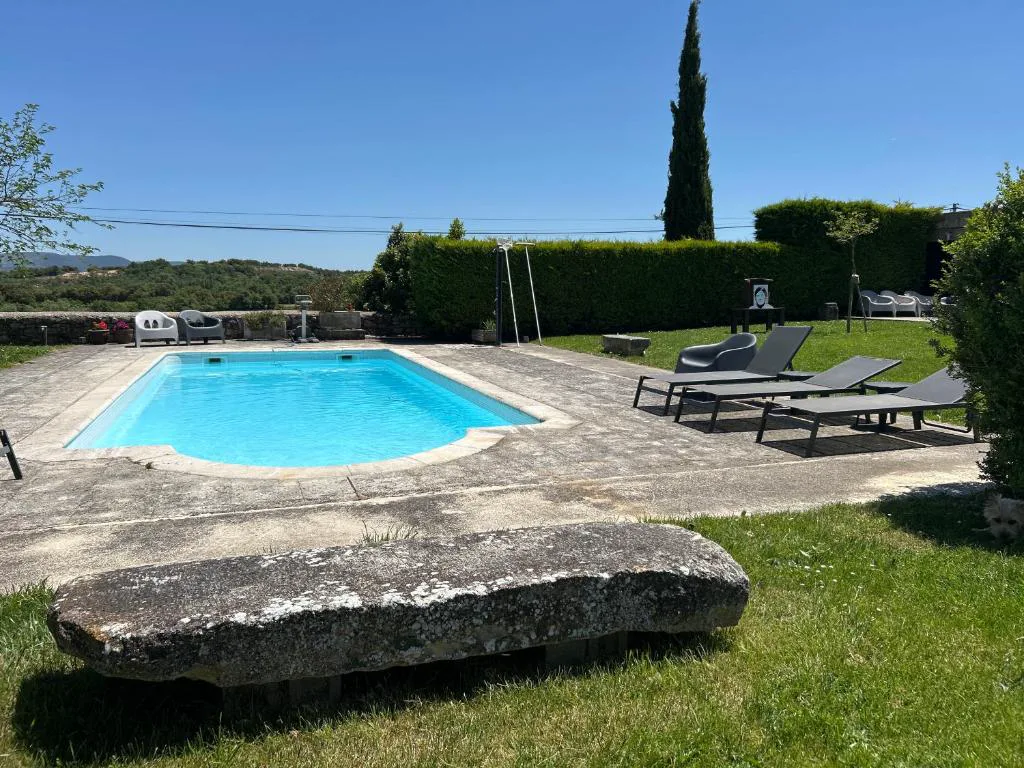 Piscina con tumbonas y una gran piedra tallada en primer plano