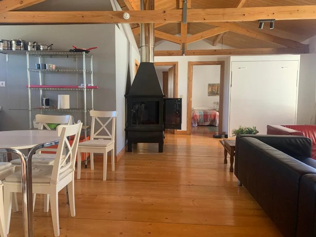 Salón abierto con estufa negra, comedor y vigas de madera