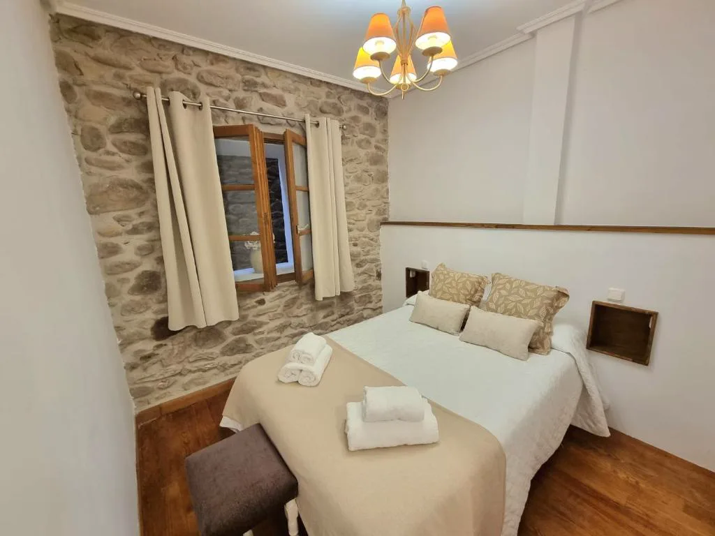Dormitorio con paredes de piedra y cama grande