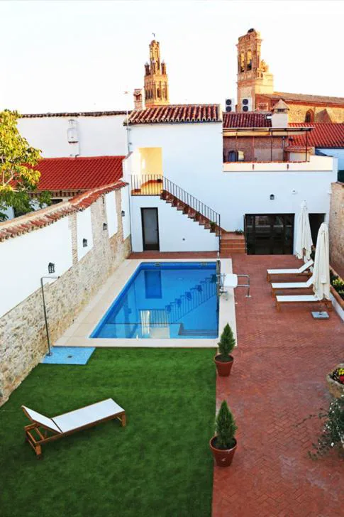 Piscina pequeña en un patio con césped y paredes blancas