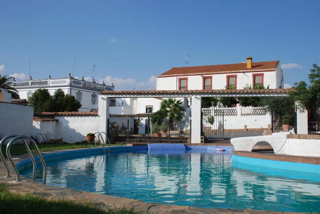 Piscina rectangular junto a una casa blanca con tejas