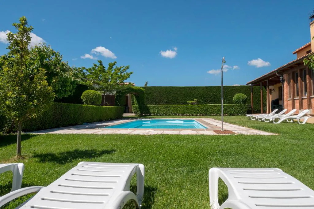 Piscina con tumbonas blancas y seto verde