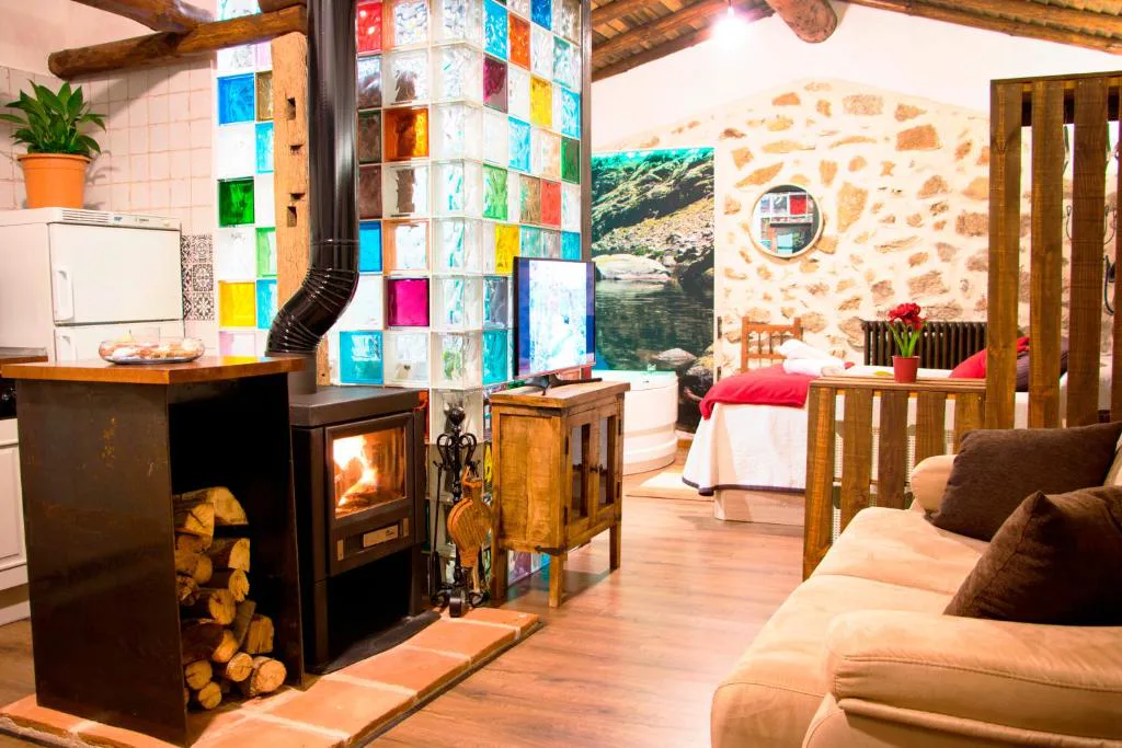 Salón con estufa de leña, cocina y pared de vidrios de colores