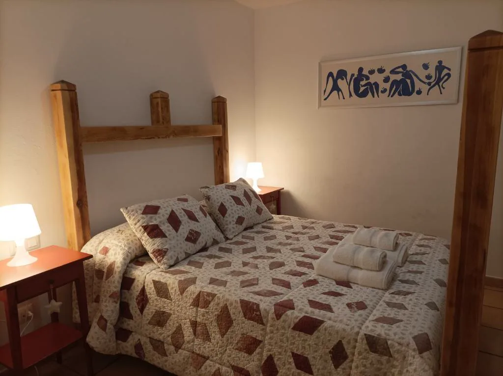 Habitación con cabecero de madera y colcha estampada
