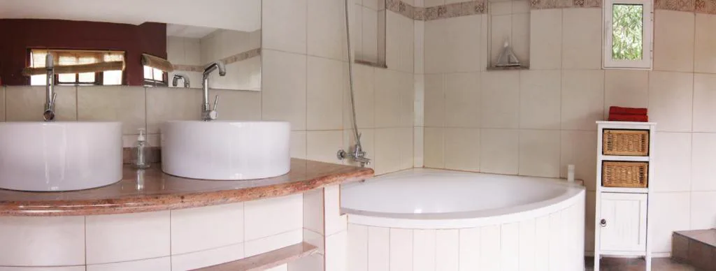 Baño con doble lavabo de piedra y bañera de hidromasaje redonda, Casa Rural El Refugio
