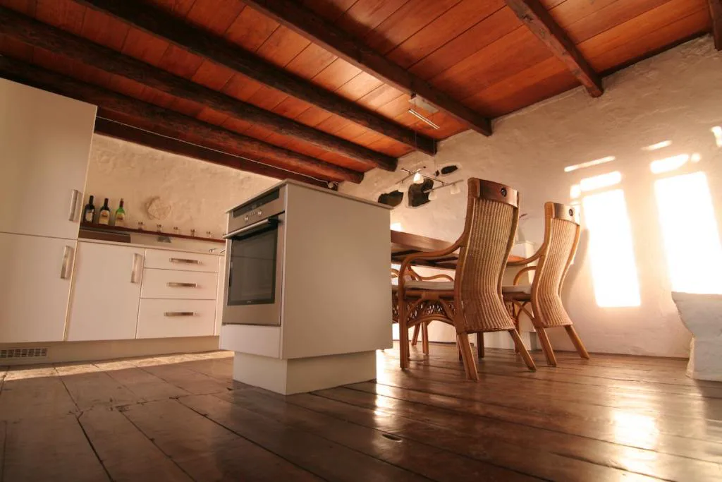 Cocina rústica con vigas de madera vista y mesa de comedor de mimbre, Casa Rural El Refugio