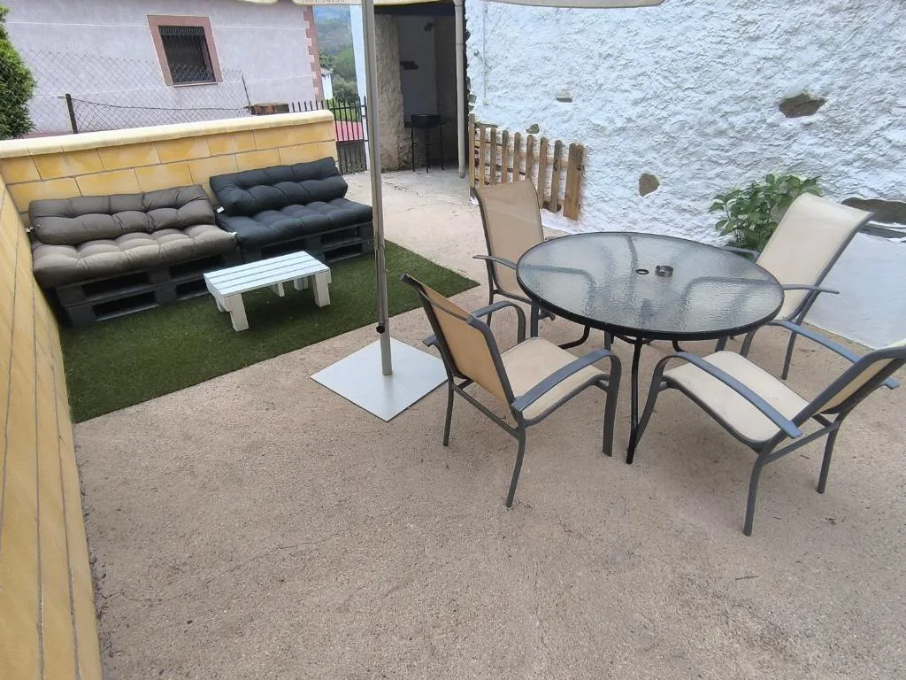 Patio con mesa y sillas junto a una pared de piedra