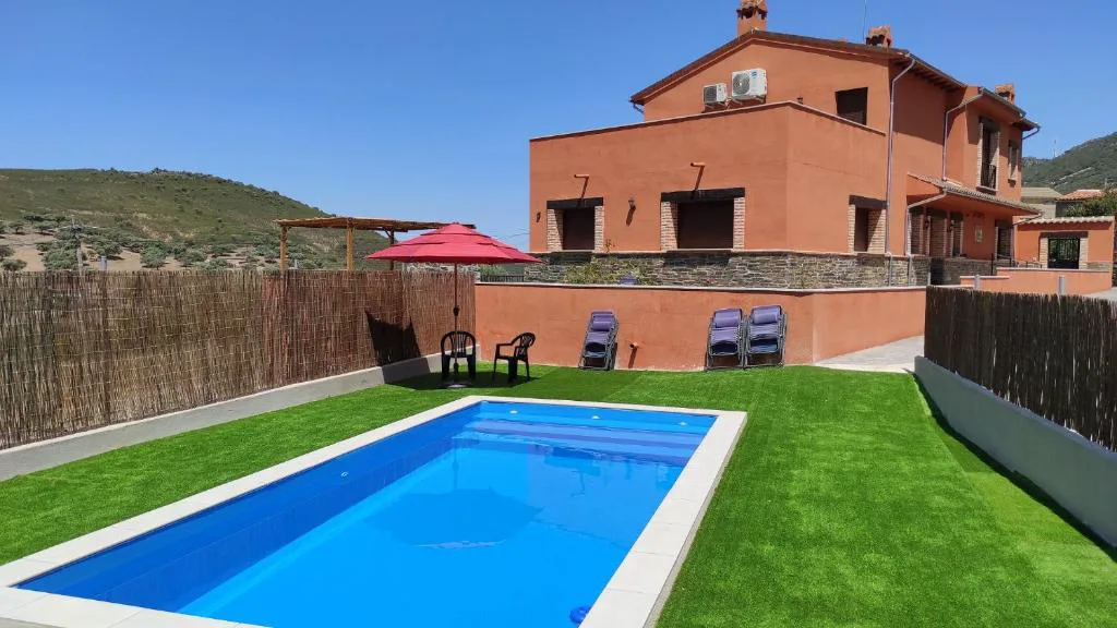 Piscina azul junto a un jardín de césped y una casa de ladrillo
