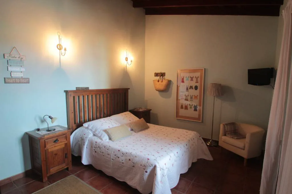 Dormitorio con cabecero de madera y techo de vigas vista, Casa Rural la Hojalata