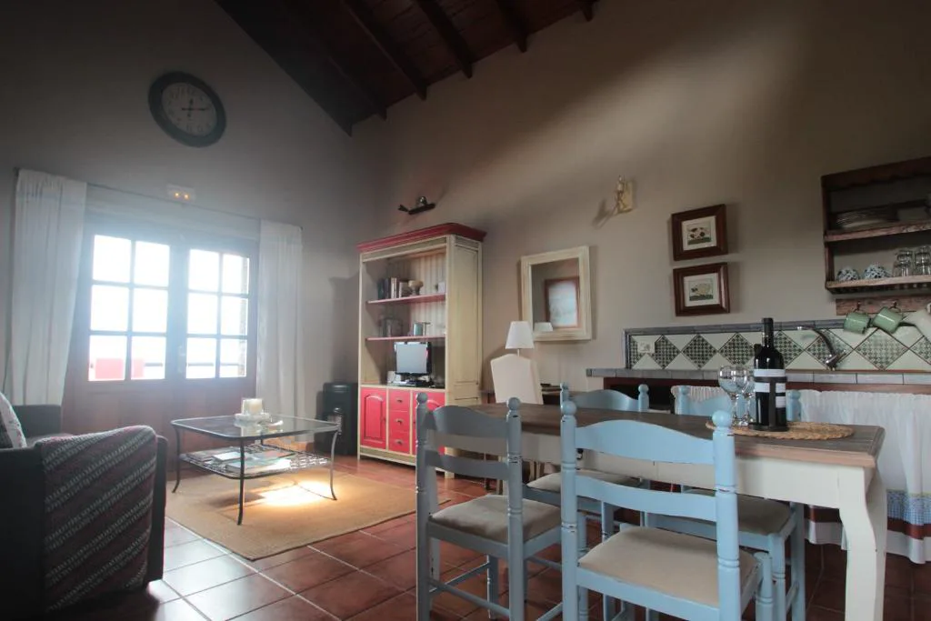 Salón con vigas de madera, reloj de pared y muebles tradicionales, Casa Rural la Hojalata