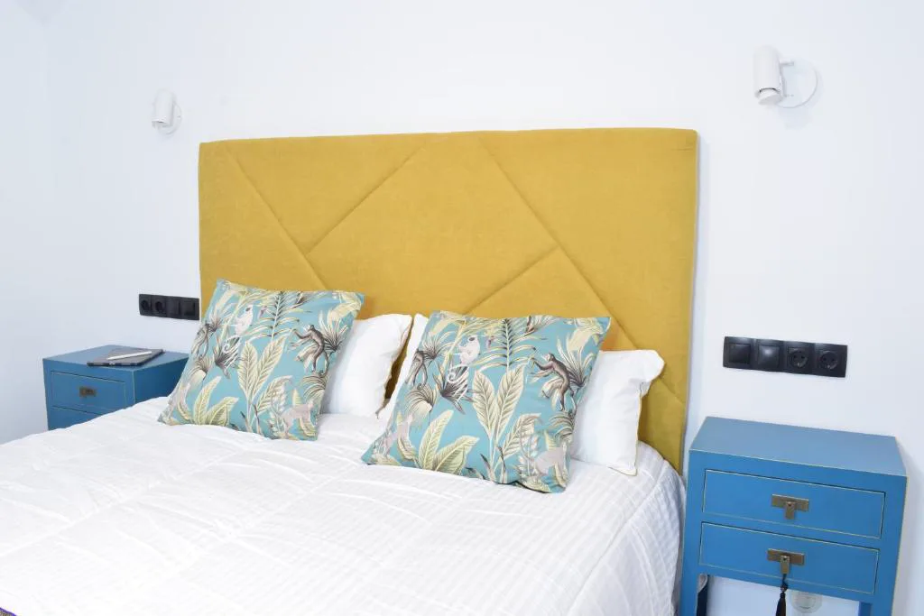 Habitación con cabecero amarillo y cojines