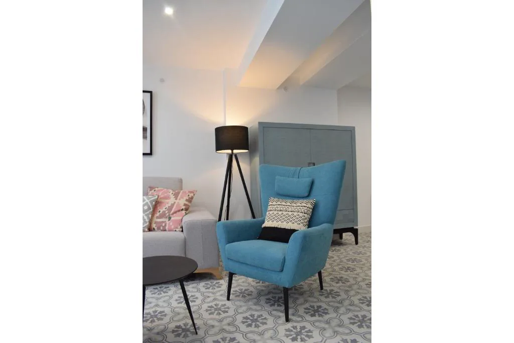 Salón con sillón azul y mesa de cristal