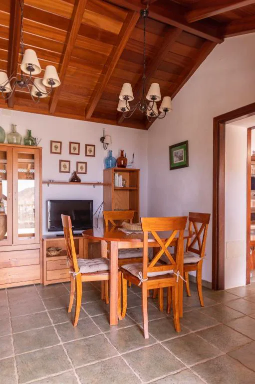 Comedor con techo de vigas de madera vista y sillas trenzadas junto a vitrina antigua, Casa Rural La Palizada