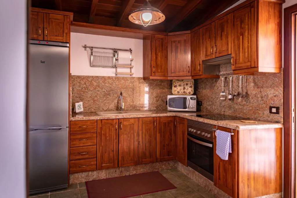 Cocina de madera maciza con encimera de granito y menaje tradicional, Casa Rural La Palizada