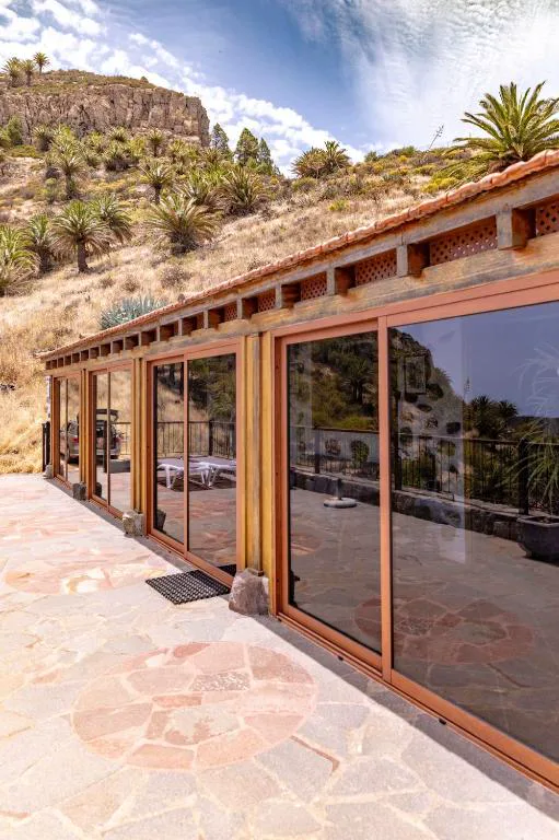 Fachada con puertas acristaladas y vistas al paisaje de palmeras y montañas de Benchijigua, Casa Rural La Palizada