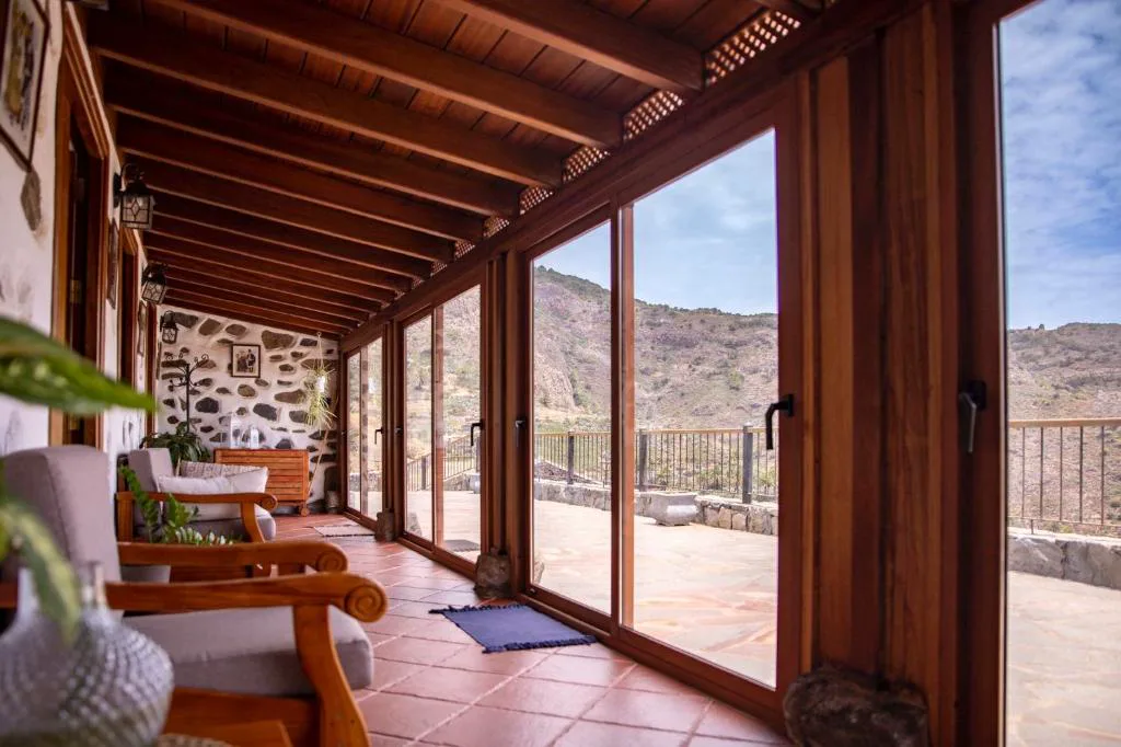 Terraza acristalada con sillones de madera y vistas al barranco de Benchijigua, Casa Rural La Palizada, La Gomera