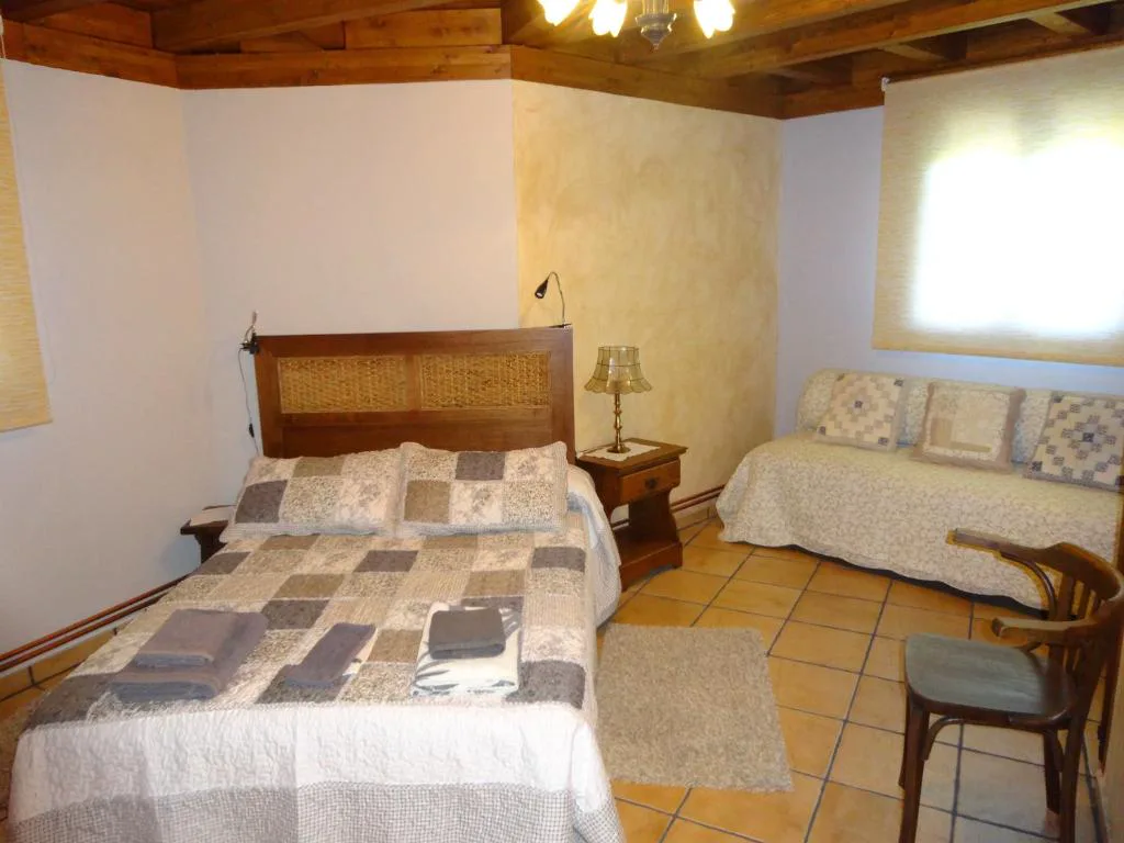 Habitación con cama de forja y pared de piedra