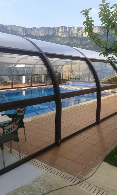 Piscina con estructura de cristal abierta al jardín