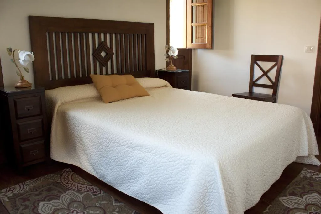Dormitorio con cabecero de madera tallada y mesillas a juego, Casa Rural Llano Campo