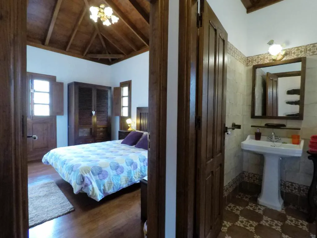 Dormitorio bajo techo de vigas de madera vista con baño anexo, Casa Rural Llano Campo
