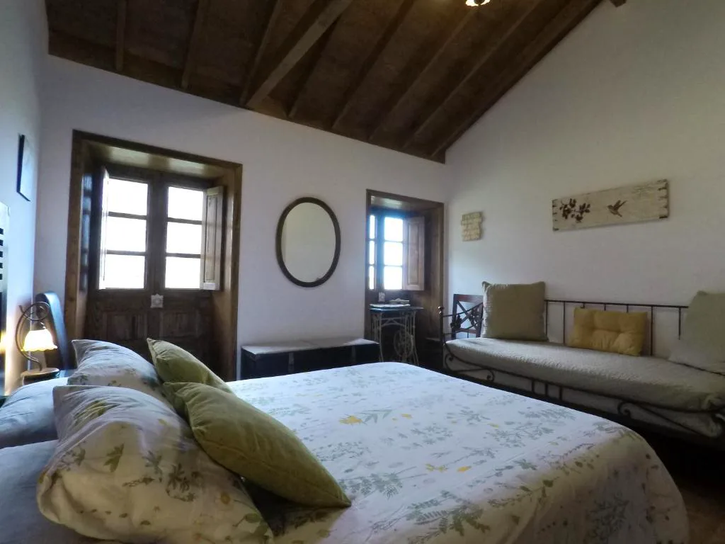 Dormitorio con techo de madera a dos aguas y cojines verdes, Casa Rural Llano Campo