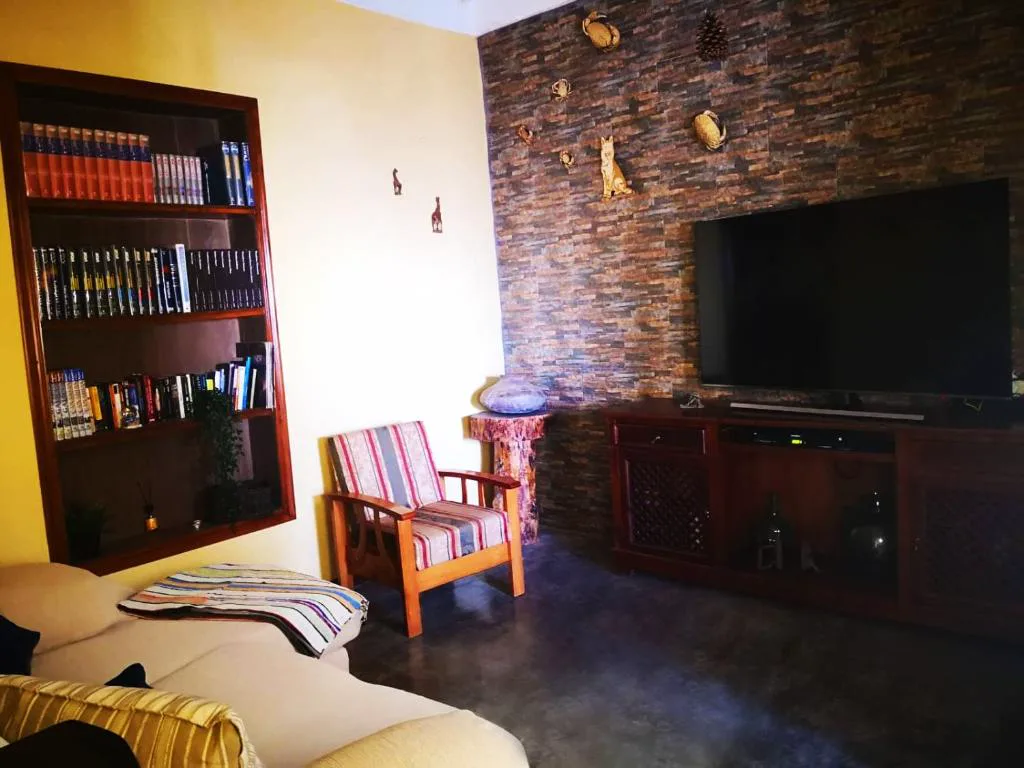 Dormitorio en tonos amarillos con puerta de madera azul abierta a un pasillo de piedra, Casa rural Los Órganos de Arguamul