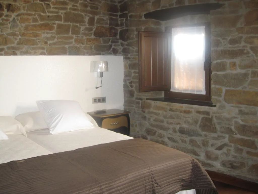 Dormitorio con pared de piedra y ropa de cama clara