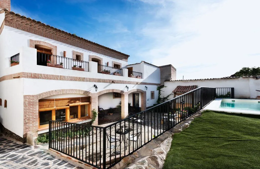Piscina en un patio junto a una casa blanca