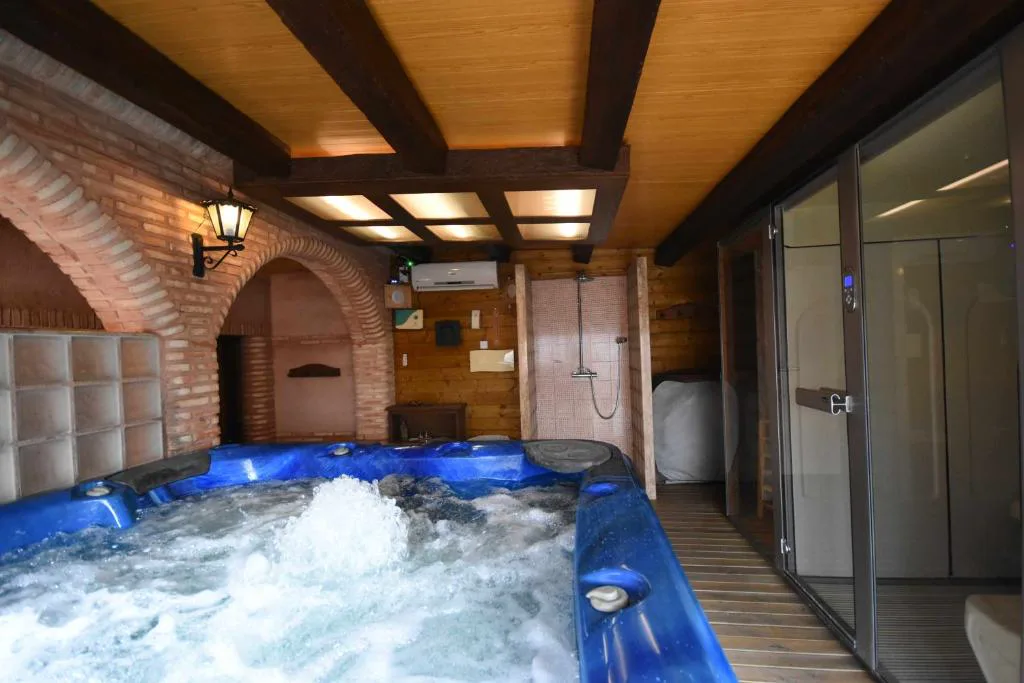 Jacuzzi azul en una sala con arco de ladrillo y techo de vigas