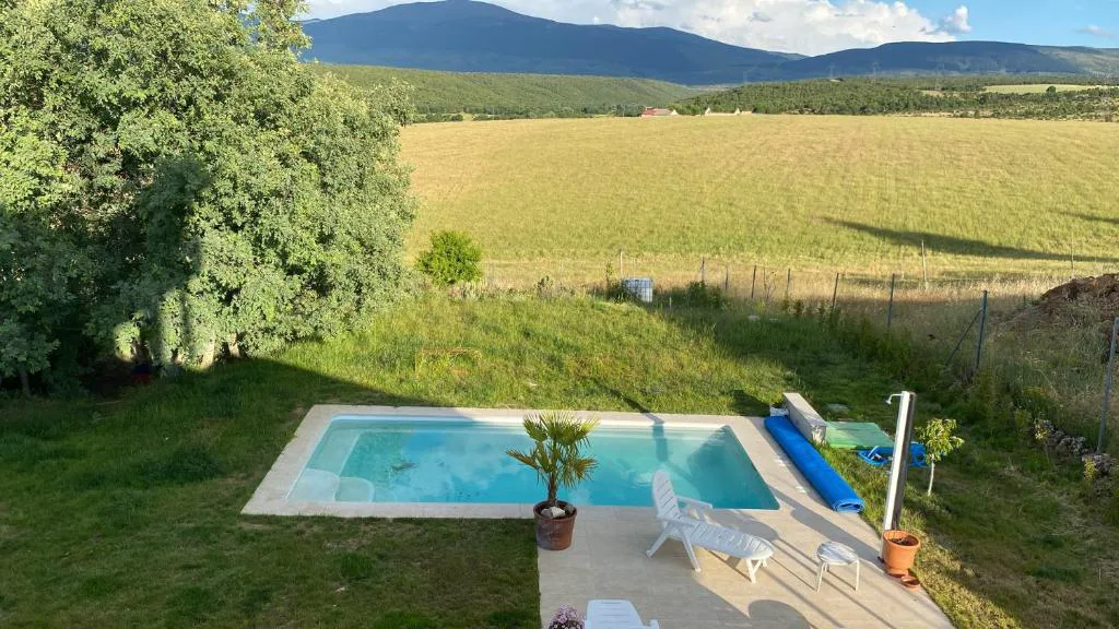 Piscina en el jardín con campos de cereal y montañas al fondo