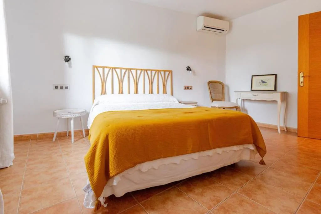 Habitación con cabecero de madera y manta naranja