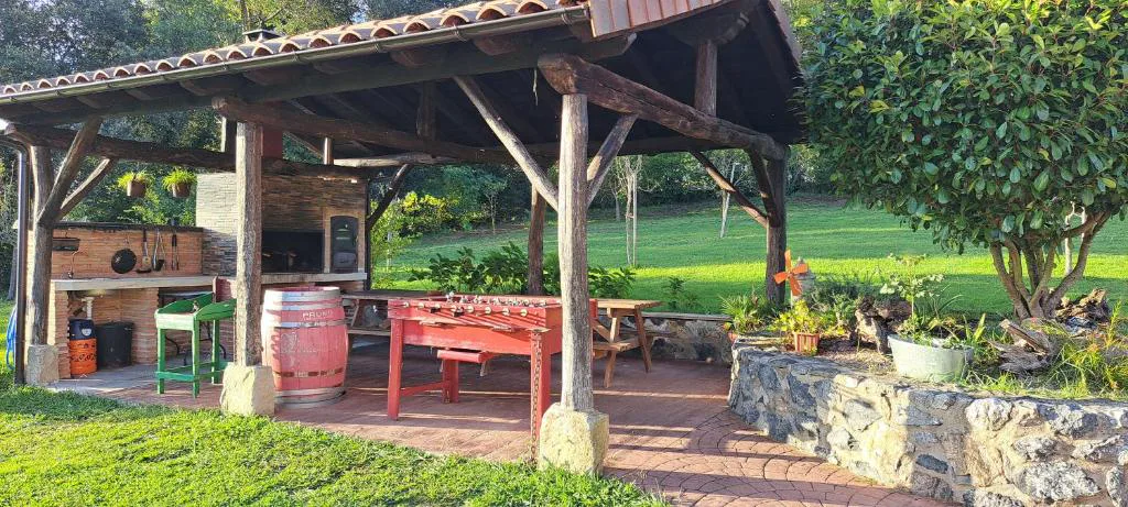 Cenador con mesas y zona de barbacoa junto al jardín